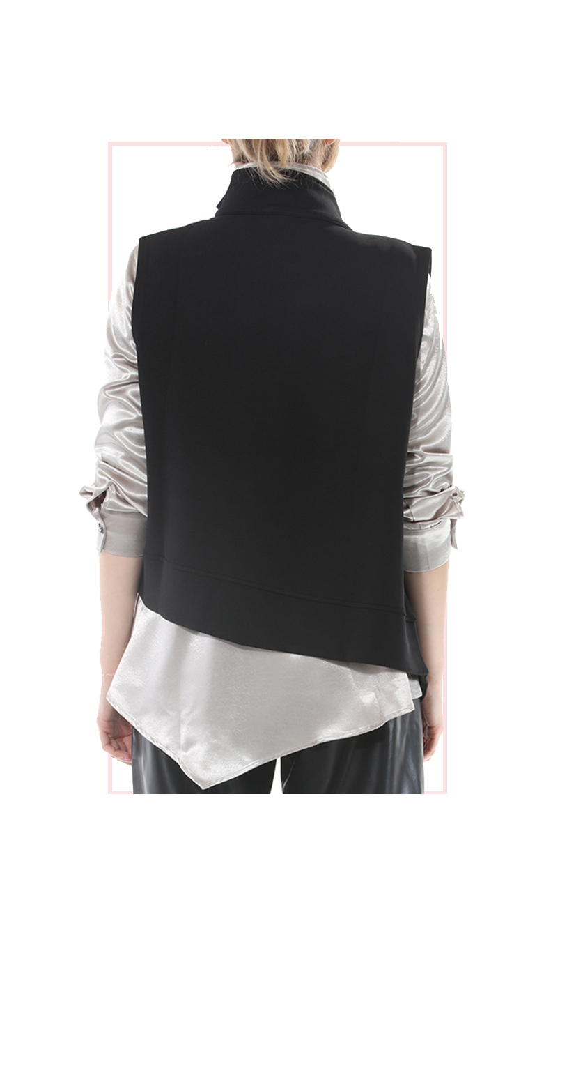 Back view of TERRA black asymmetric zip vest layered over a white blouse