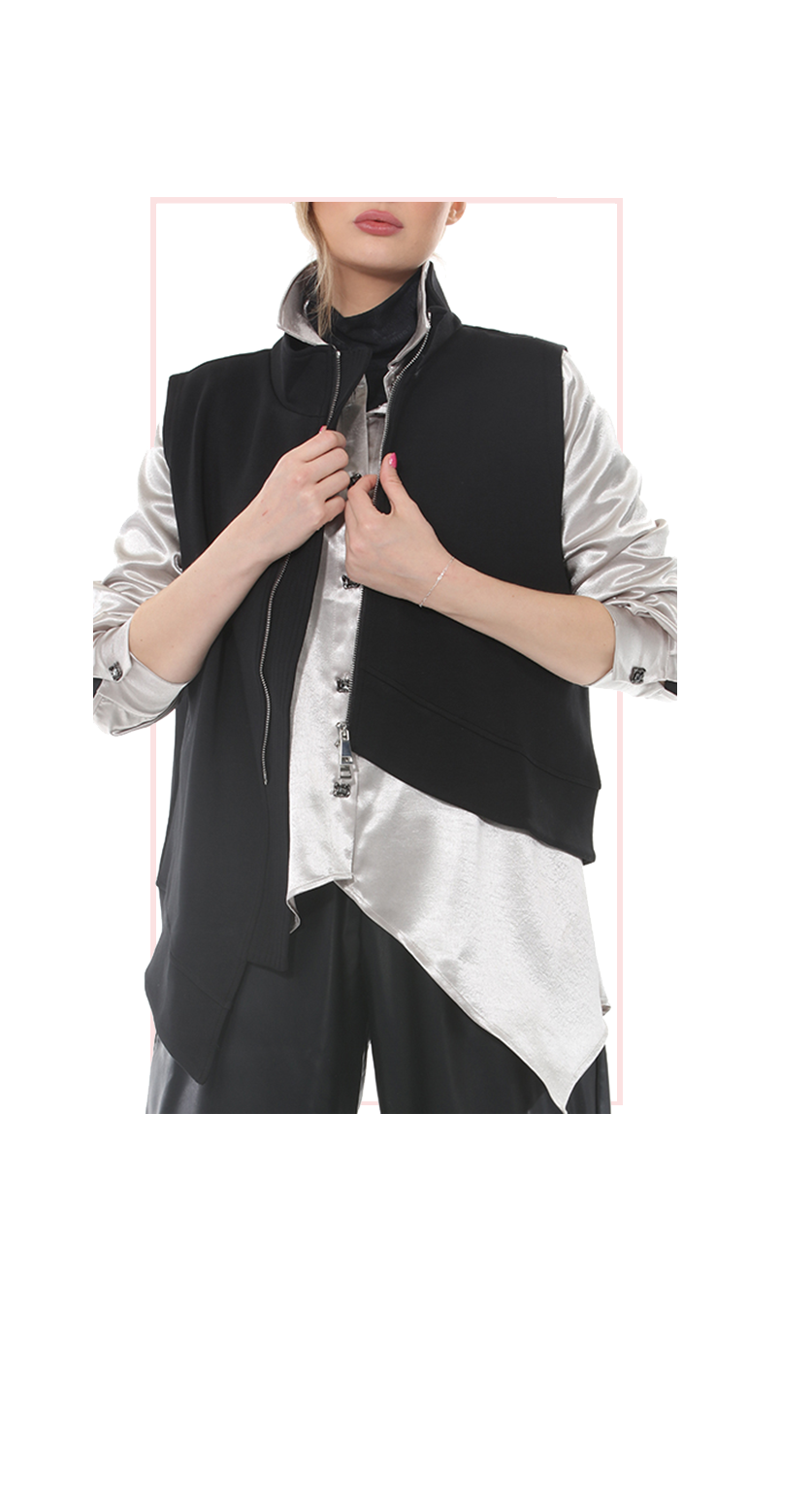 Woman wearing TERRA black asymmetric zip vest layered over a white blouse