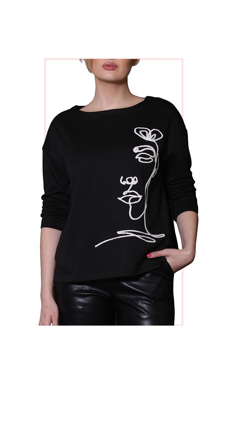 Black sweater with white floral design worn by a person on a white background
