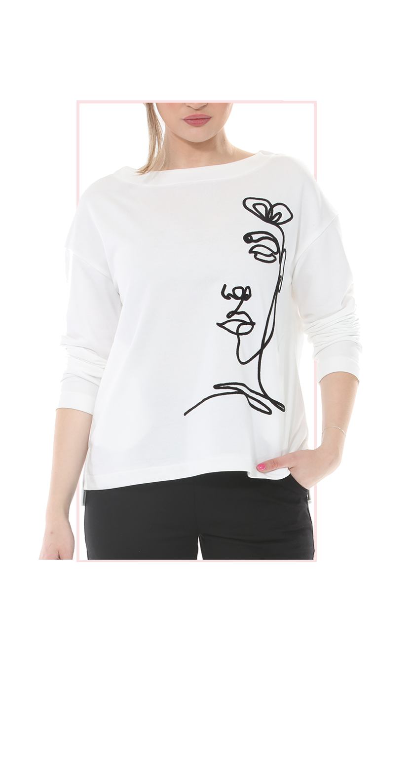White sweater with black floral design worn by a person on a white background